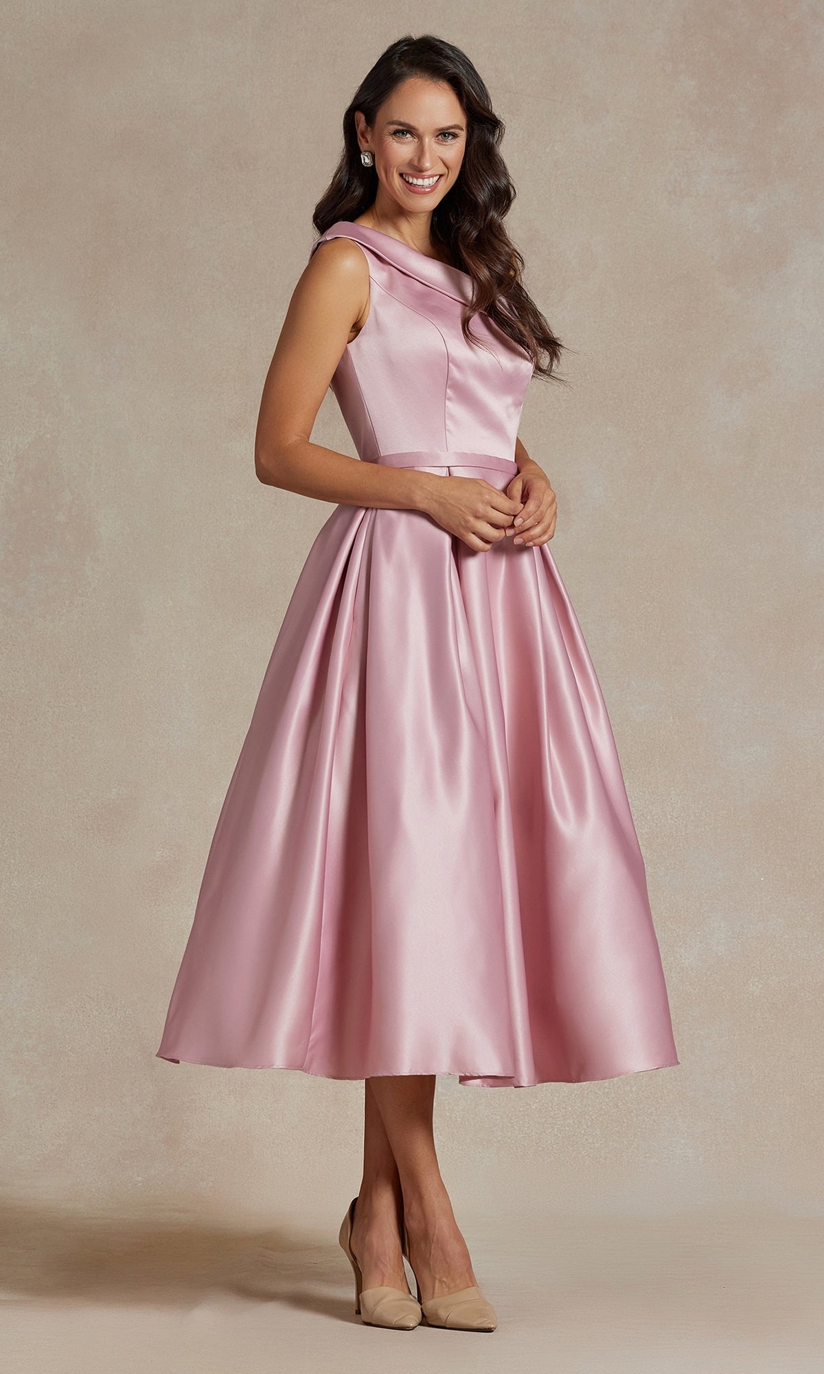 A woman in the One-Shoulder Simple Tea-Length Party Dress JE931 and beige heels stands against a neutral backdrop, smiling with hands clasped.